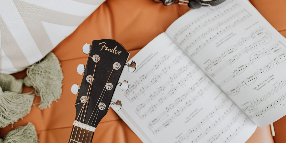 Guitarra y partituras abiertas, simbolizando la experiencia musical personalizada que Spotify Wrapped transforma en una narrativa identitaria que impulsa la participación del usuario.